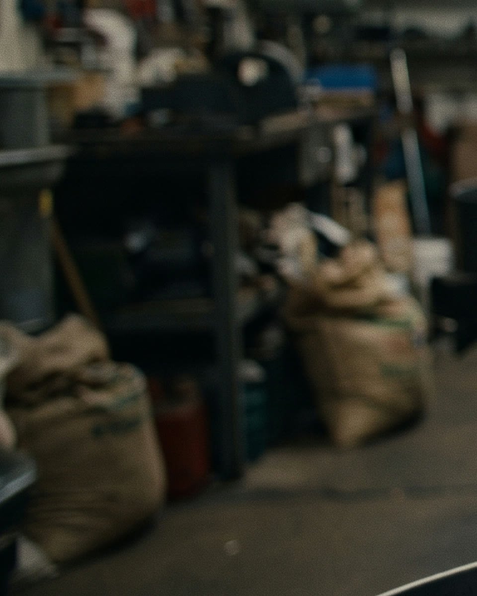 Des sacs de café vert posés au sol dans l'atelier de torréfaction.